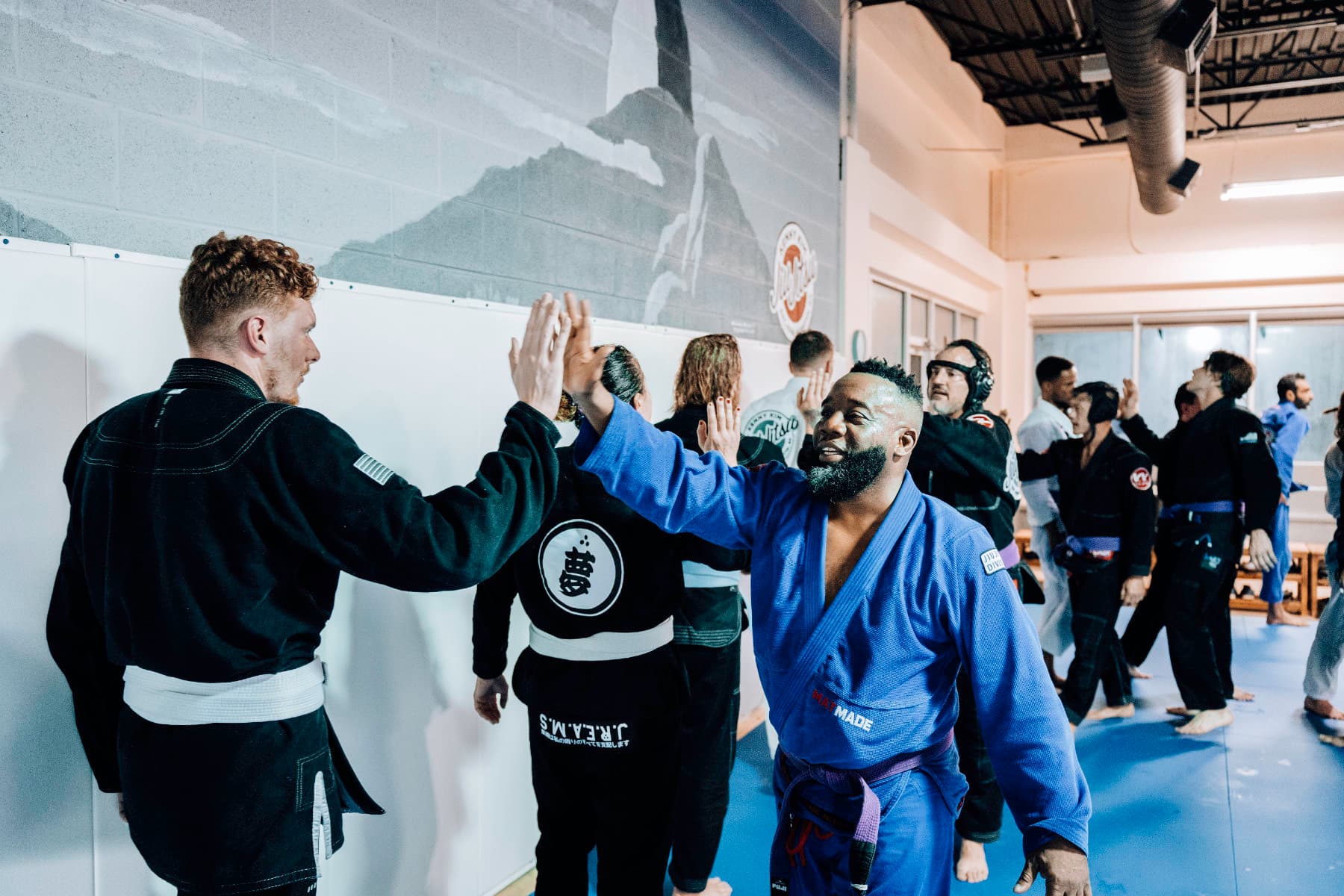 Adult Brazilian Jiu Jitsu Students at Kenny Kim BJJ in Marietta GA high-fiving after an intense rolling session