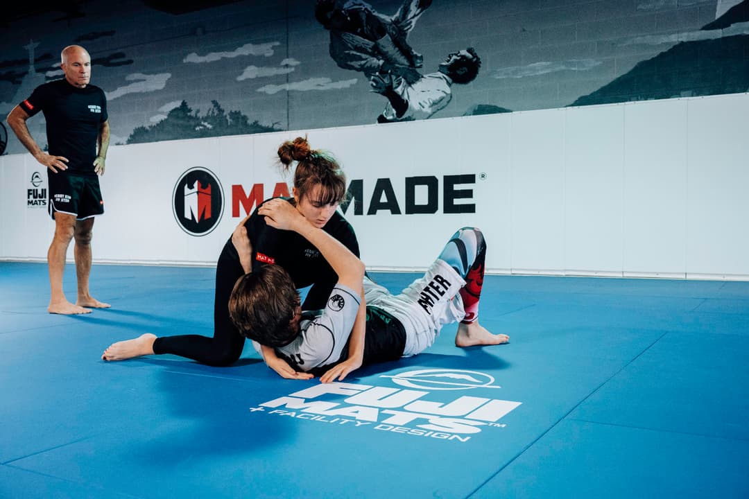 Brazilian Jiu Jitsu Teenagers at Kenny Kim BJJ in Marietta GA rolling on the mats girl vs boy instructor waiting closeby