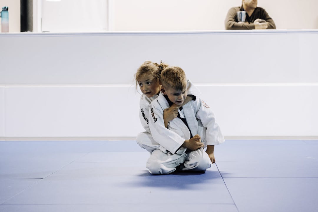 Brazilian Jiu Jitsu Kids at Kenny Kim BJJ in Marietta GA caught in the moment of rolling in guard and practicing new techniques from their instructors