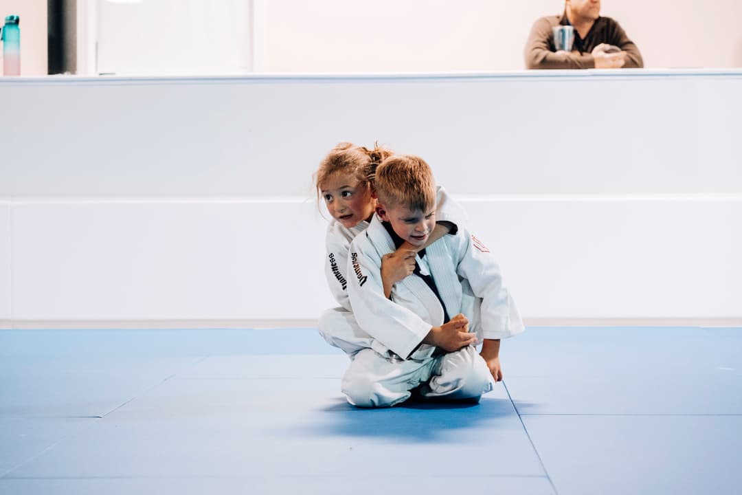 Brazilian Jiu Jitsu Kids at Kenny Kim BJJ in Marietta GA caught in the moment of rolling in guard and practicing new techniques from their instructors