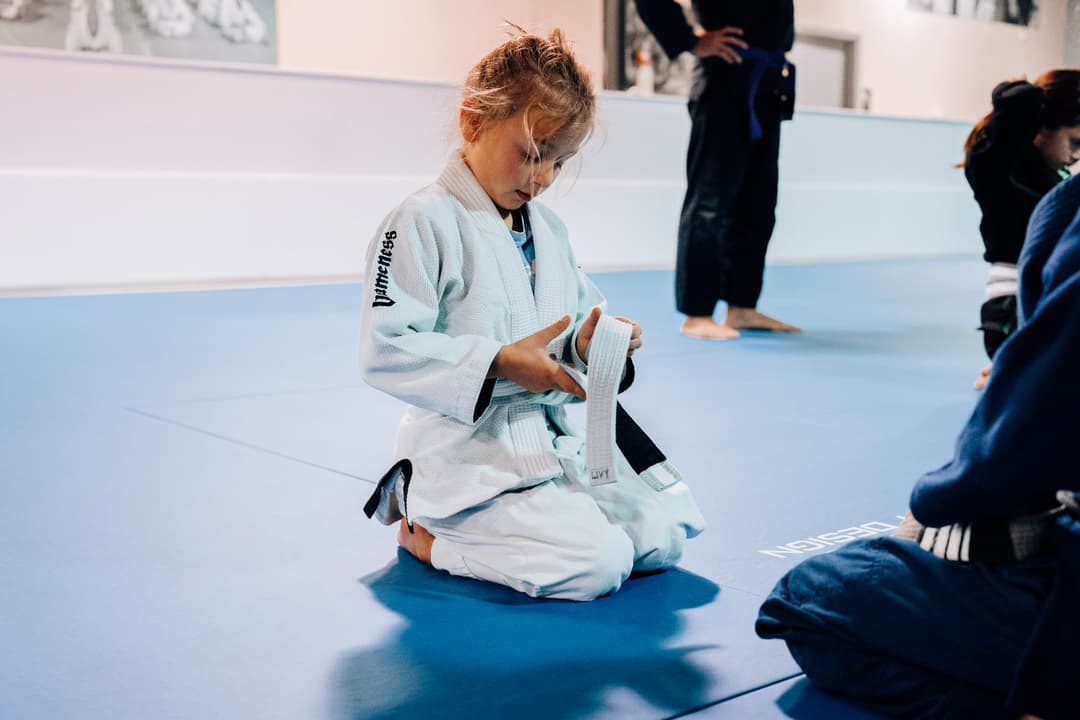 Brazilian Jiu Jitsu Girl at Kenny Kim BJJ in Marietta GA tying her belt before class