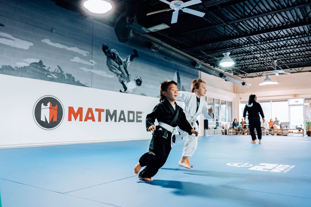 Brazilian Jiu Jitsu Kids at Kenny Kim BJJ in Marietta GA running around on the mats warming up before class starts