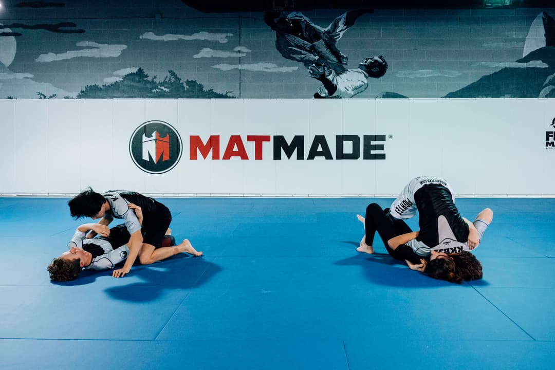 Brazilian Jiu Jitsu Teenagers at Kenny Kim BJJ in Marietta GA rolling on the mats, two groups of sparring partners next to one another